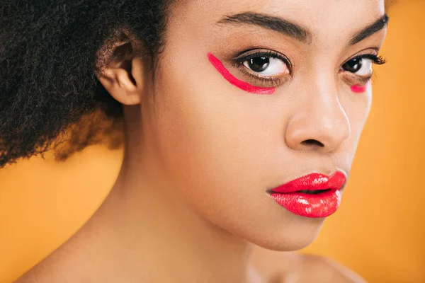 Portrait en gros plan de jeune femme avec un maquillage rouge créatif isolé sur jaune — Photo de stock