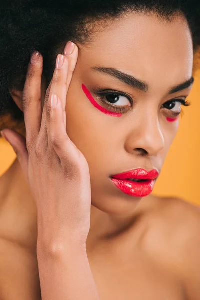 Atractiva joven con maquillaje rojo creativo aislado en amarillo - foto de stock