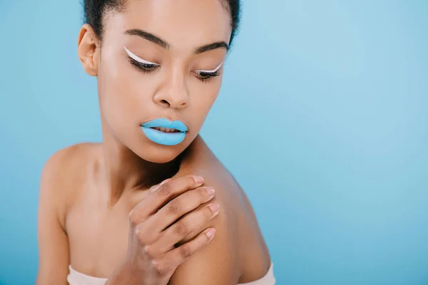 Seductora mujer afroamericana con maquillaje creativo y labios azules en azul - foto de stock