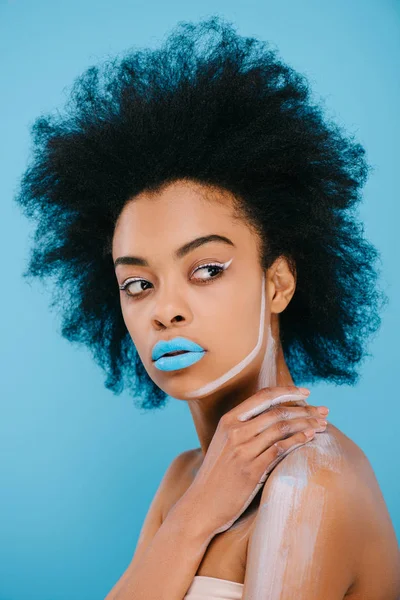 Atractiva joven con maquillaje creativo y labios azules aislados en azul - foto de stock