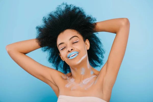 Jeune femme souriante avec maquillage créatif et lèvres bleues isolées sur bleu — Photo de stock