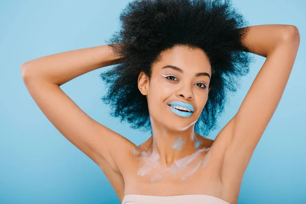 Feliz joven con maquillaje creativo y labios azules aislados en azul - foto de stock