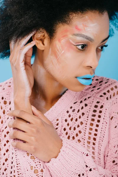 Young african american woman with creative makeup in sweater isolated on blue — Stock Photo