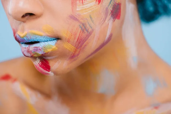 Обрізаний знімок жінки з різнокольоровими штрихами на обличчі на синьому — стокове фото