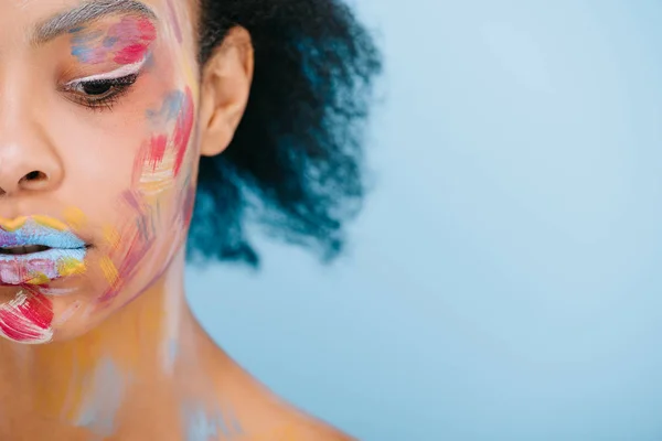 Cropped shot of beautiful young woman with colorful strokes on face isolated on blue — Stock Photo