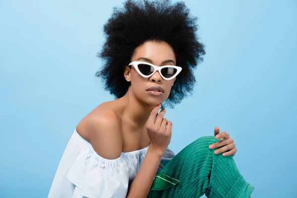 Attraktive junge Frau in stylischem schulterfreien Top und Sonnenbrille auf blauem Grund — Stockfoto