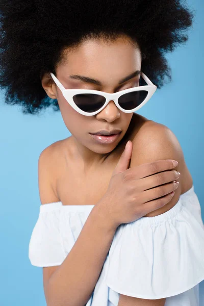 Nahaufnahme einer jungen Frau in stylischem schulterfreien Top und Sonnenbrille isoliert auf blauem Grund — Stockfoto