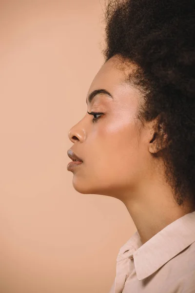 Vue latérale d'une jolie femme afro-américaine isolée sur beige — Photo de stock