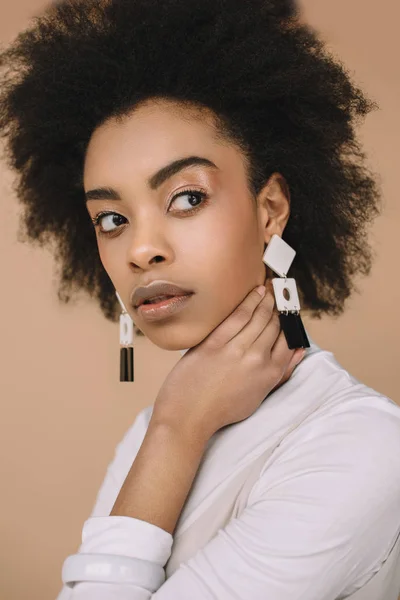 Close-up portrait of attractive young woman in stylish clothes with earrings isolated on beige — Stock Photo