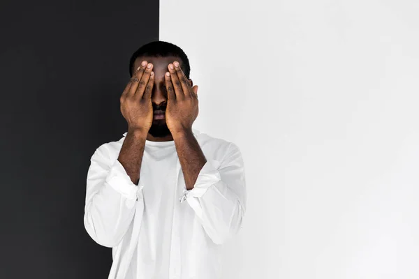 Hombre afroamericano con estilo en ropa blanca cerrando los ojos con las manos — Stock Photo