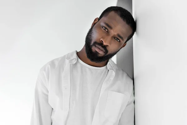 Guapo hombre afroamericano elegante en ropa blanca apoyada en la pared — Stock Photo