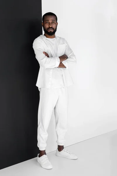 Stylish african american man standing with crossed arms and looking at camera — Stock Photo