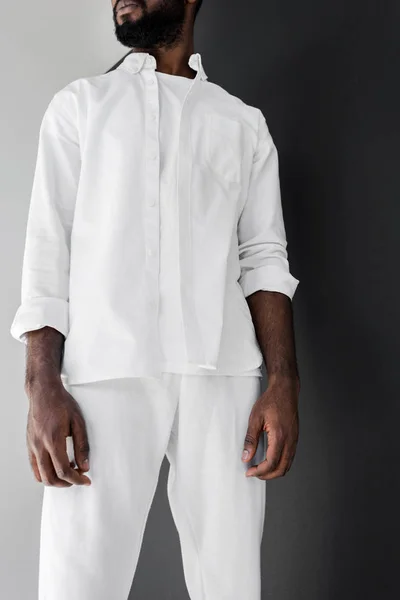 Imagen recortada de hombre afroamericano con estilo de pie en ropa blanca - foto de stock