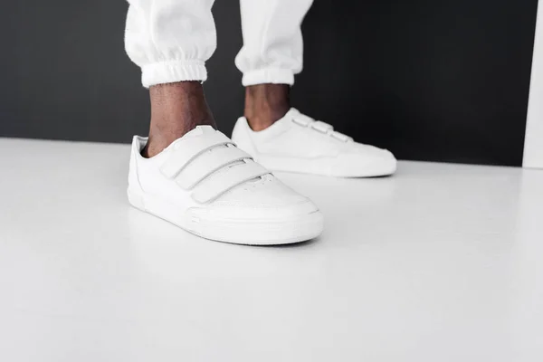 Imagem cortada de homem americano africano elegante em pé em gumshoes branco — Fotografia de Stock