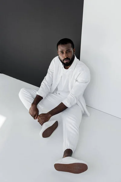 High angle view of handsome stylish african american man sitting on floor near black and white wall — Stock Photo