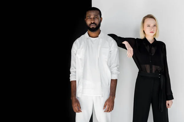 Stylish blonde girlfriend leaning on african american boyfriend near black and white wall — Stock Photo