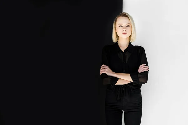 Приваблива стильна блондинка в чорному одязі, що стоїть з схрещеними руками — стокове фото