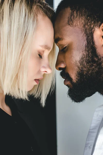 Vue latérale du couple multiculturel touchant le front — Photo de stock