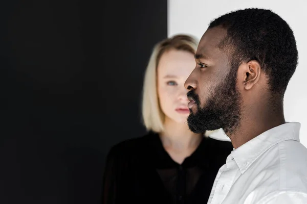 Vista laterale del bel ragazzo afroamericano in piedi davanti alla ragazza bionda — Foto stock