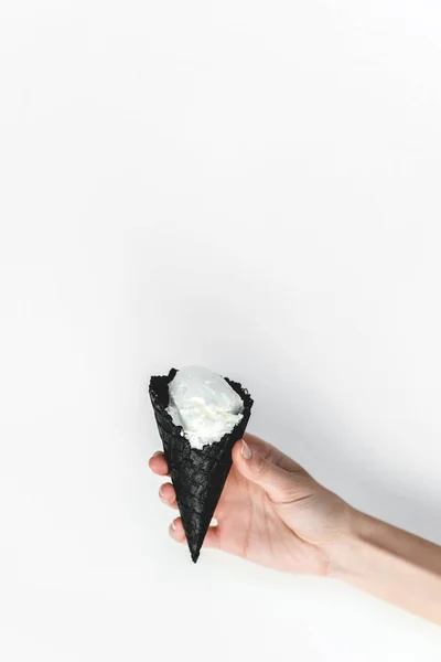 Cropped image of woman holding ice cream in black cone isolated on white — Stock Photo