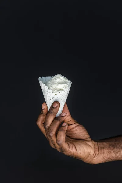 Cropped image of african american man holding white ice cream cone isolated on black — Stock Photo