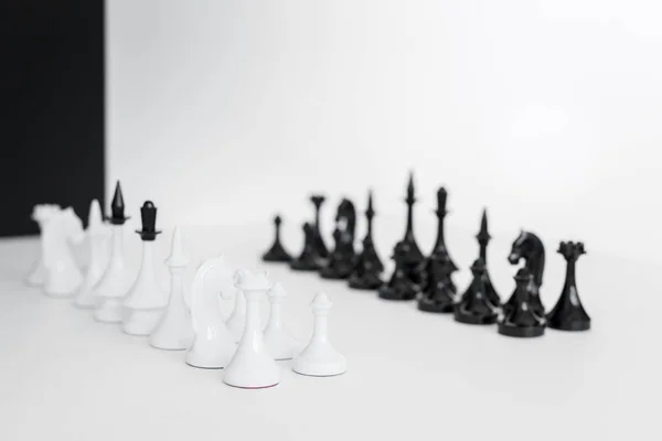 Figuras de ajedrez sobre mesa blanca cerca de pared en blanco y negro - foto de stock