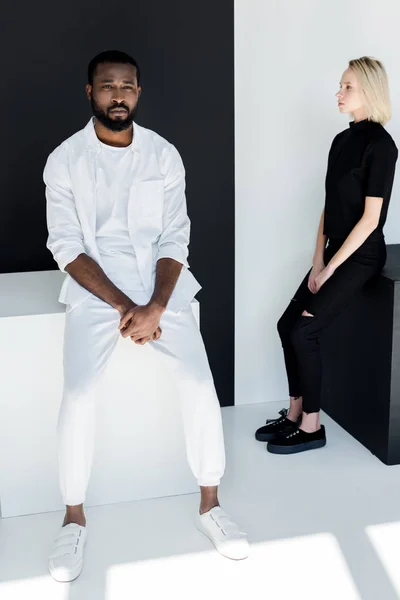 Multikulturelles Paar sitzt auf schwarzen und weißen Würfeln — Stockfoto