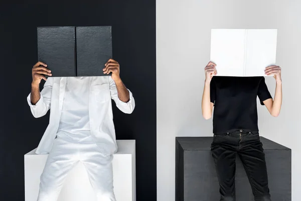 African american boyfriend and girlfriend covering faces with books — Stock Photo