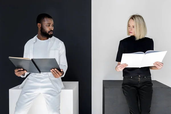 Couple multiculturel tenant des livres en noir et blanc, concept yin yang — Photo de stock