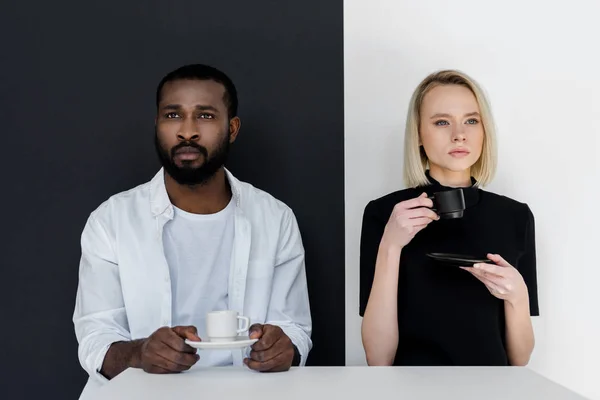 Multikulturelles Paar hält Tassen Kaffee in der Hand und schaut weg — Stockfoto
