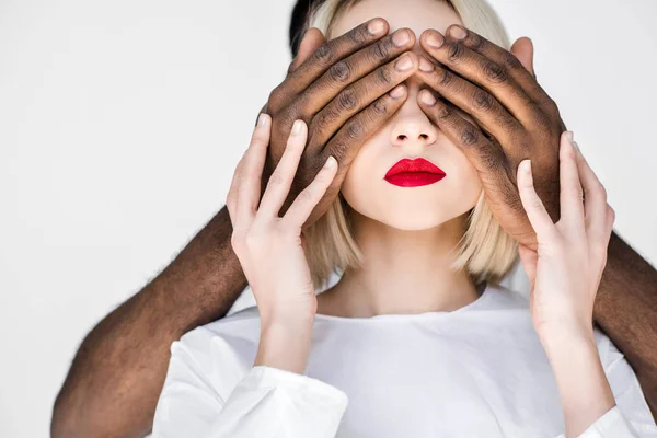 Cropped image of african american boyfriend closing eyes of blonde girlfriend isolated on white — Stock Photo