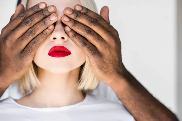 Cropped image of african american boyfriend closing eyes of blonde girlfriend — Stock Photo
