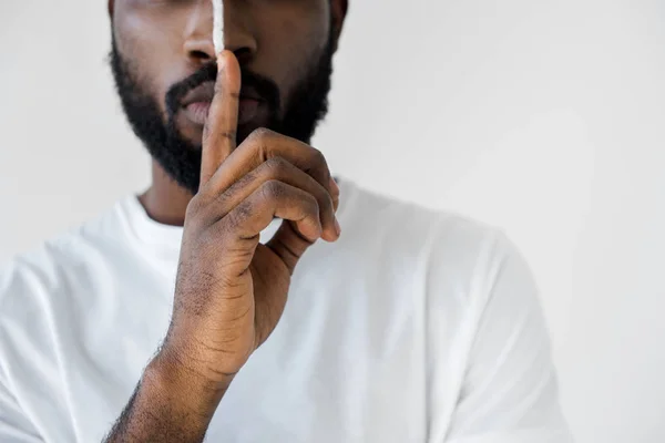 Imagem cortada do homem americano africano com listra branca no rosto mostrando sinal de silêncio isolado no branco — Fotografia de Stock