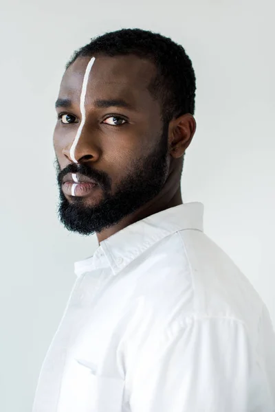 Guapo hombre afroamericano con estilo con raya blanca en la cara aislado en blanco - foto de stock