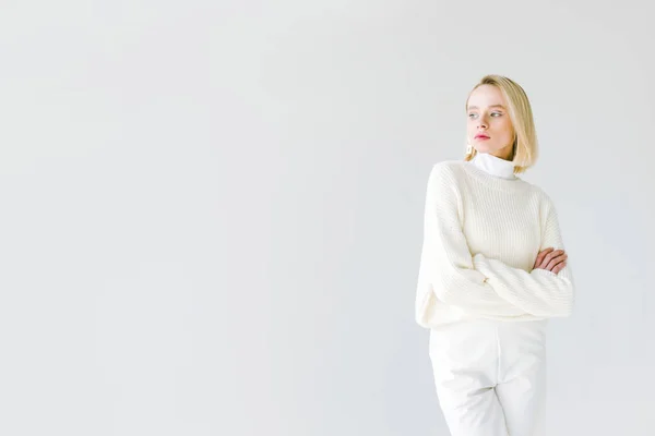 Schöne stylische blonde Frau in weißen Kleidern, die mit verschränkten Armen auf weiß isoliert steht — Stockfoto