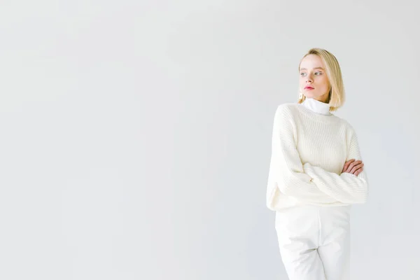 Hermosa mujer rubia con estilo en ropa blanca de pie con brazos cruzados aislados en blanco - foto de stock