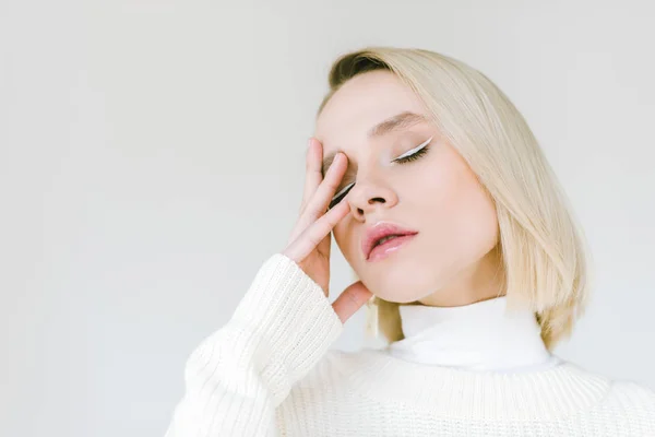 Portrait de belle femme blonde élégante en vêtements blancs touchant le visage avec la main isolée sur blanc — Photo de stock