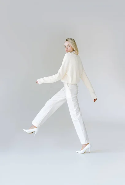 Vue latérale de la femme blonde élégante attrayante marchant en vêtements blancs sur blanc — Photo de stock