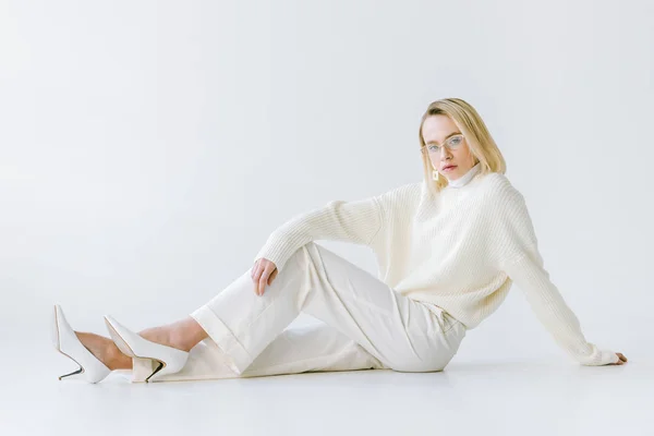 Atractiva mujer rubia con estilo en ropa blanca sentado en el suelo blanco — Stock Photo