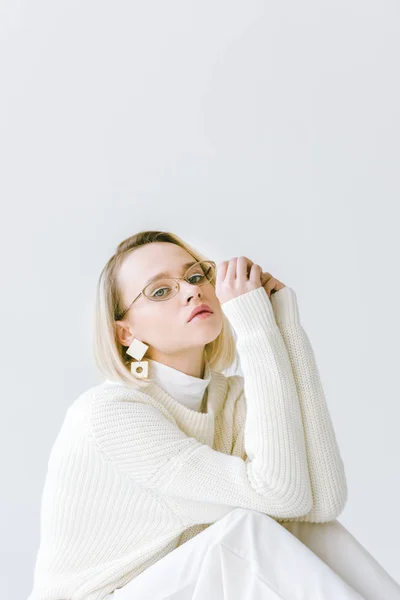 Красива стильна блондинка в білому одязі сидить ізольовано на білому — стокове фото