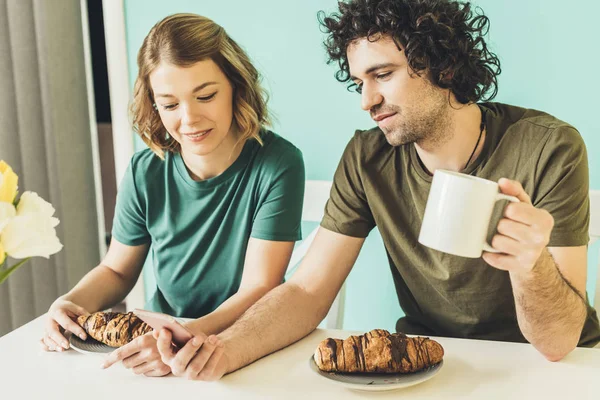 Sorrindo casal usando smartphone enquanto tomando café da manhã juntos — Fotografia de Stock