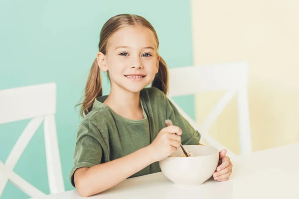 Nettes kleines Kind frühstückt und lächelt in die Kamera — Stockfoto
