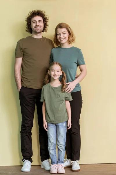 Ganzkörperansicht einer glücklichen Familie mit einem Kind, das zusammen steht und in die Kamera lächelt — Stockfoto