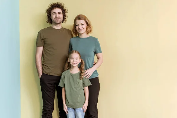 Familia feliz con un niño de pie juntos y sonriendo a la cámara - foto de stock