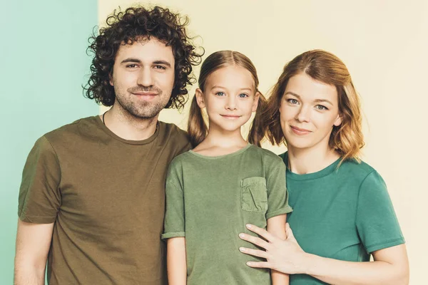 Счастливая молодая семья в футболках, улыбающаяся в камеру вместе — стоковое фото