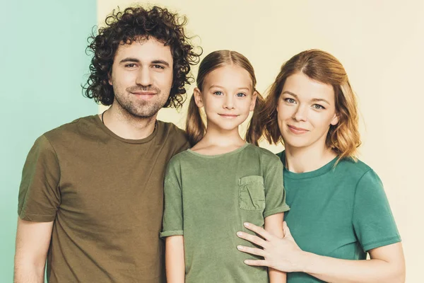 Feliz joven familia en camisetas sonriendo a la cámara juntos - foto de stock