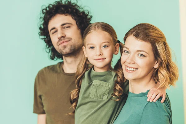 Retrato de feliz jovem família em camisetas sorrindo para a câmera juntos — Fotografia de Stock