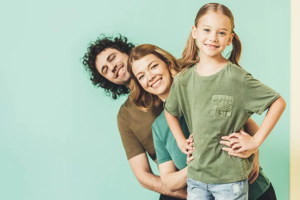 Happy parents with cute little daughter wearing t-shirts and smiling at camera — Stock Photo