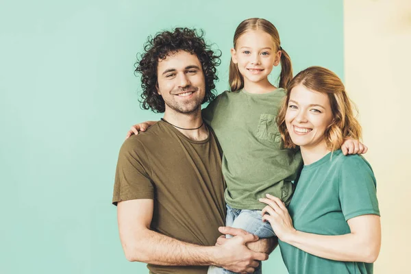Happy parents carrying adorable little daughter and smiling at camera — Stock Photo
