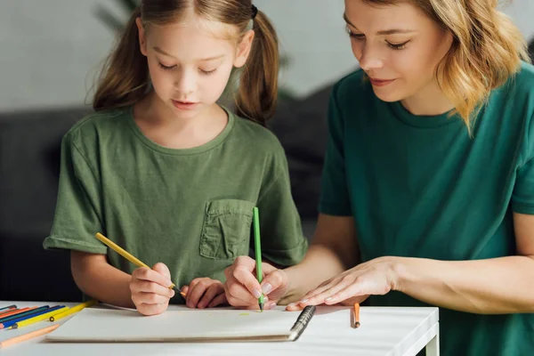 Recortado tiro de madre e hija dibujo con lápices de colores en casa - foto de stock
